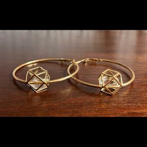 Gold colored hoop earrings with geometric charm